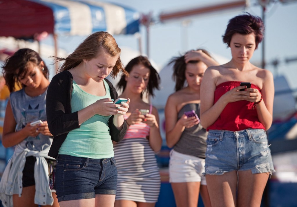 Millenial teen girls staring at their smartphones